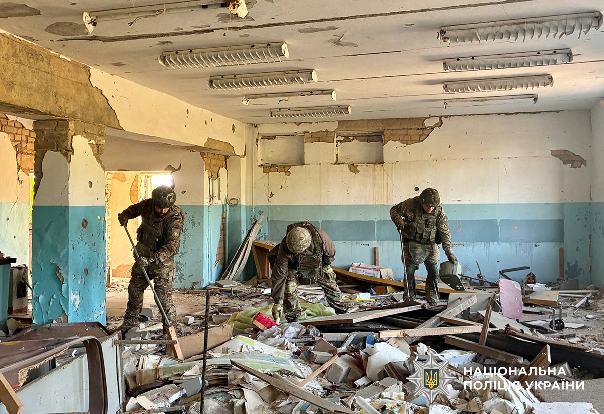 три поліцейські-вибухотехніки обстежують сильно пошкоджене приміщення