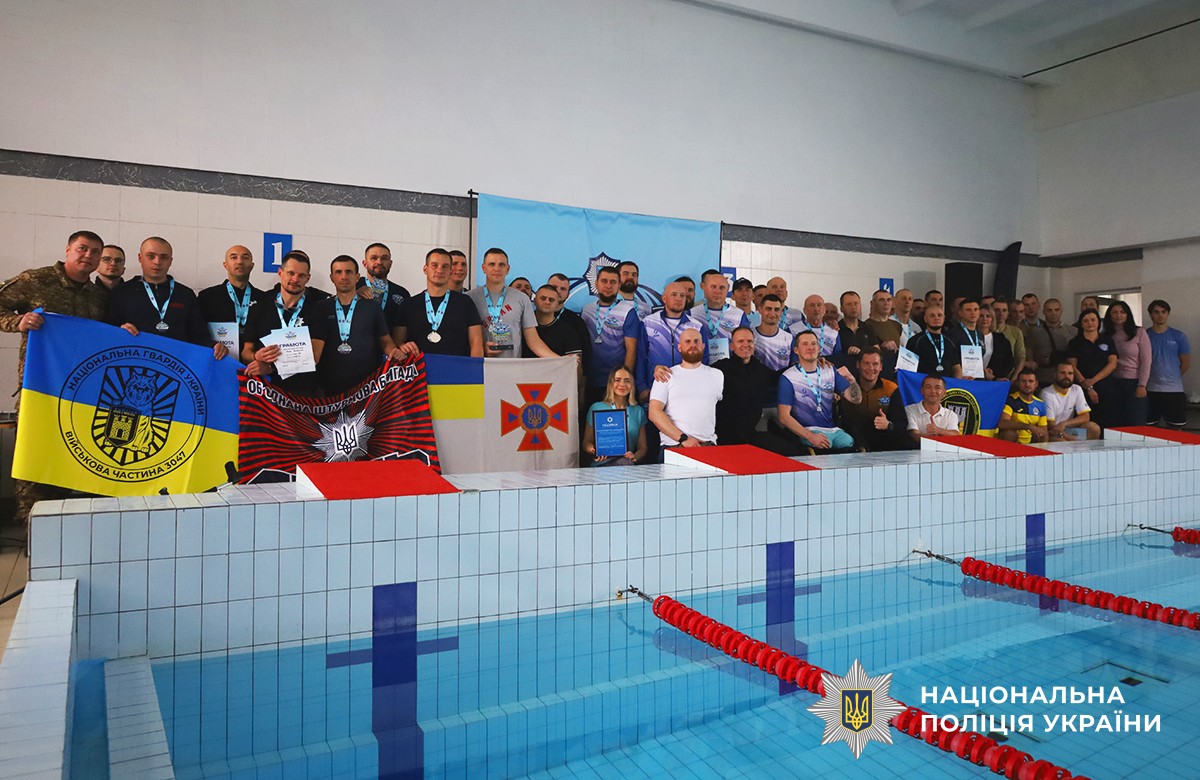 На фото спільно позують усі учасники заходу біля бортика басейну, де видно прозору блакитну воду. Позаду них розташований банер з написом «МВС Незламні» та емблемою проєкту.