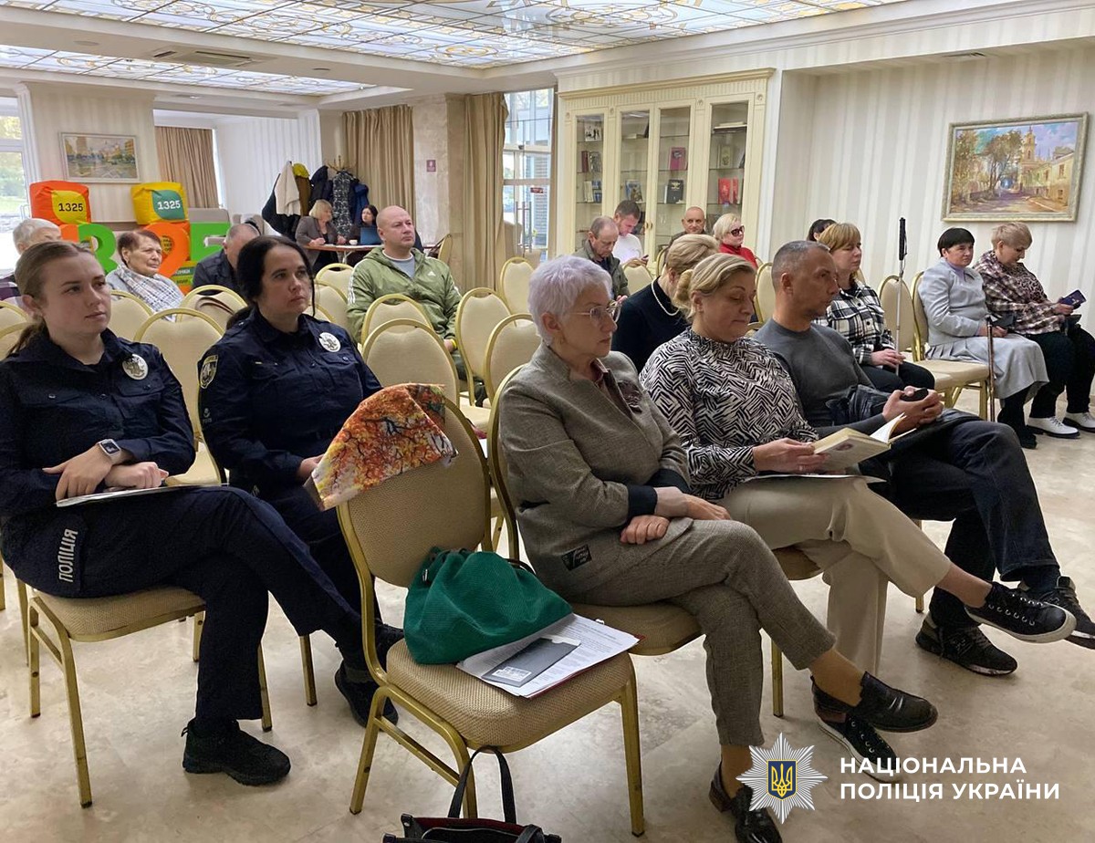 Близько десяти учасників зустрічі сидять в залі на стільцях та слухають доповідачів