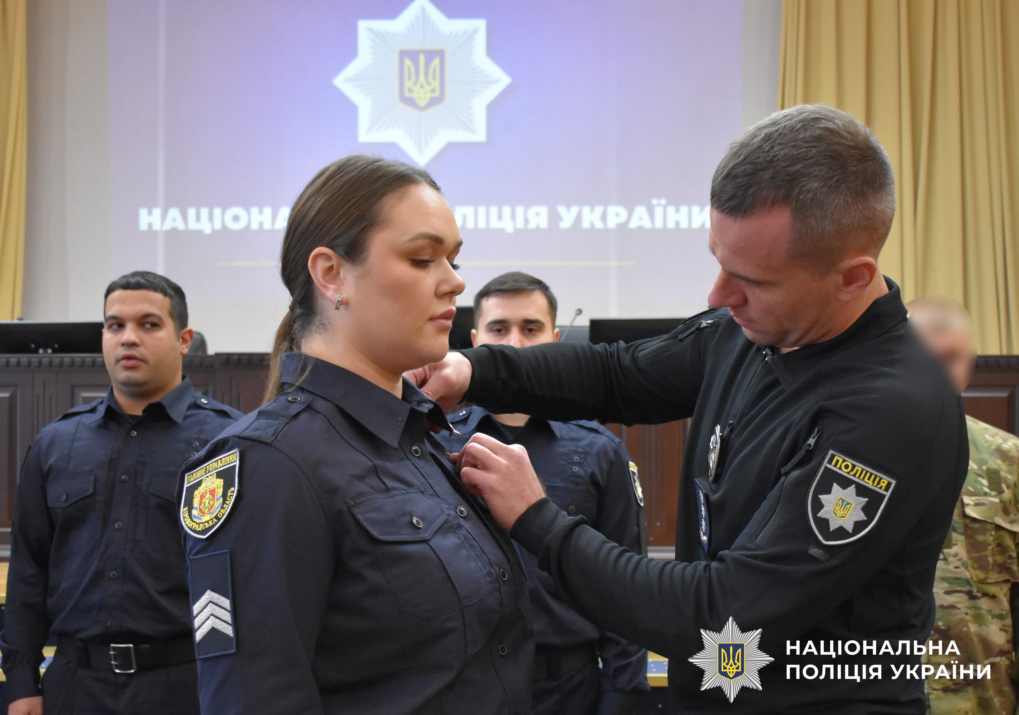 заступник керівника поліції кріпить жетон поліцейській