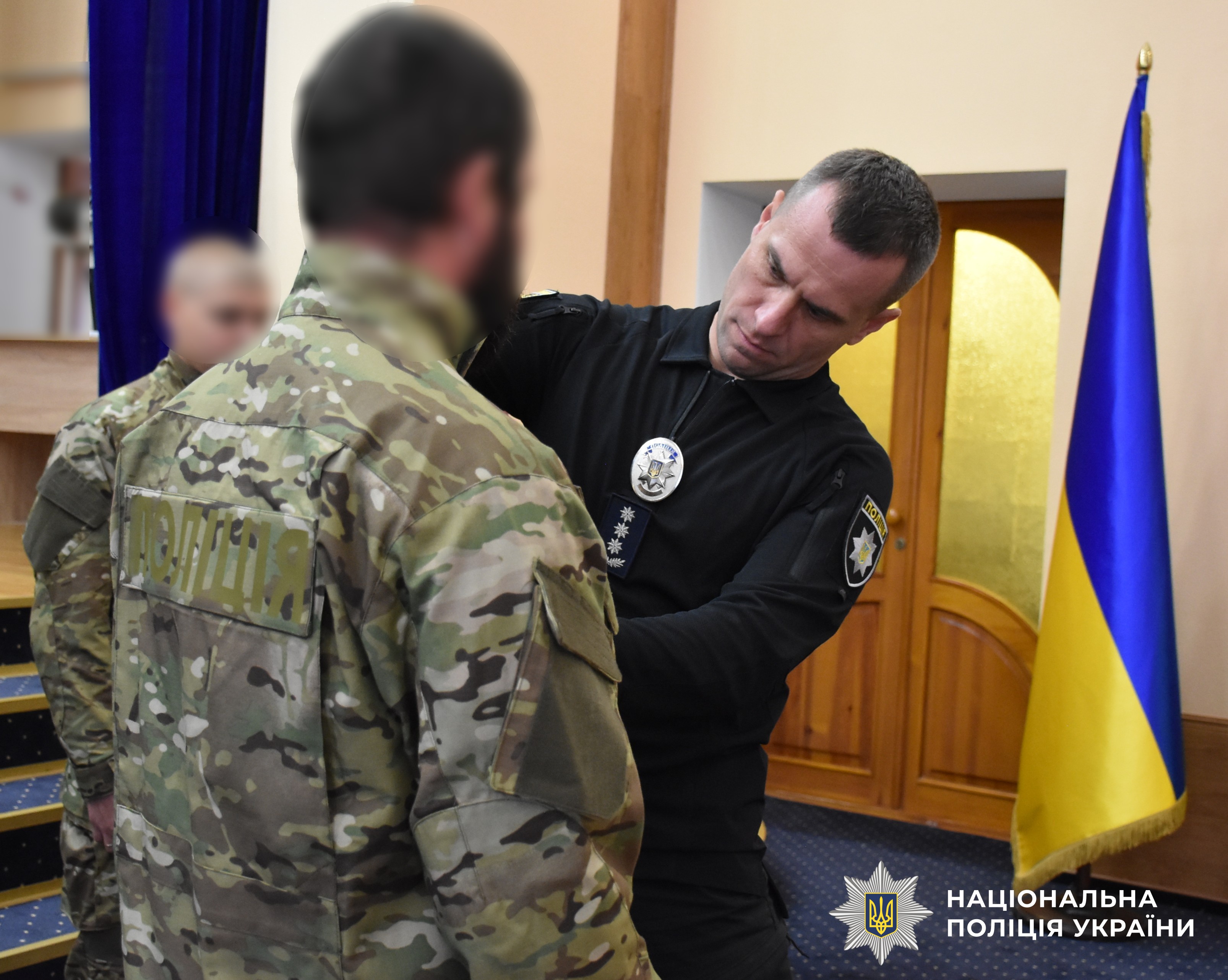 заступник керівника поліції кріпить жетон поліцейському