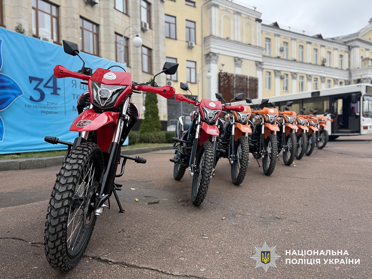 Червоні та помаранцеві мотоцикли стоять в ряд.