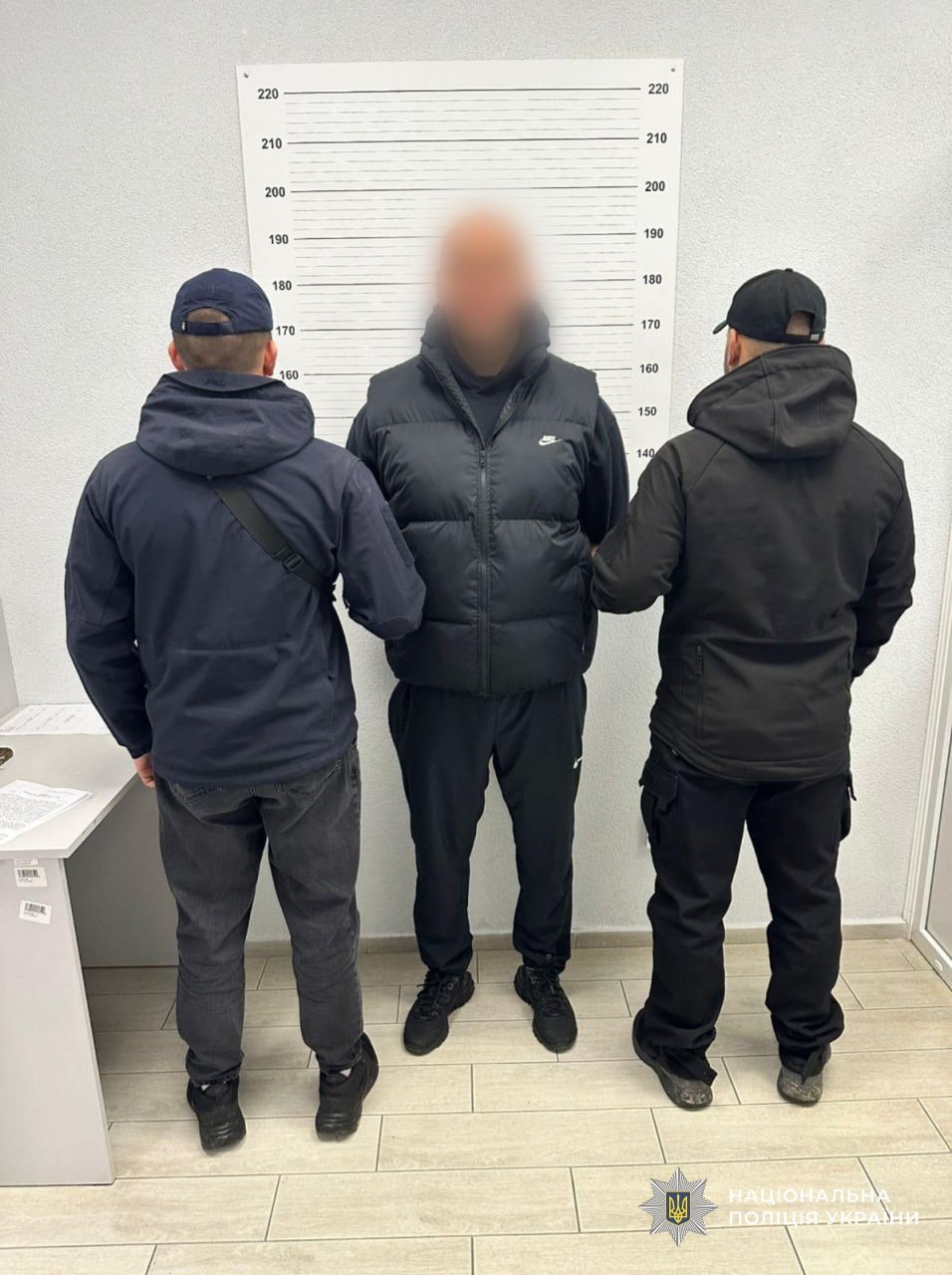 Двоє поліцейських тримають одного із затриманих членів ОЗГ