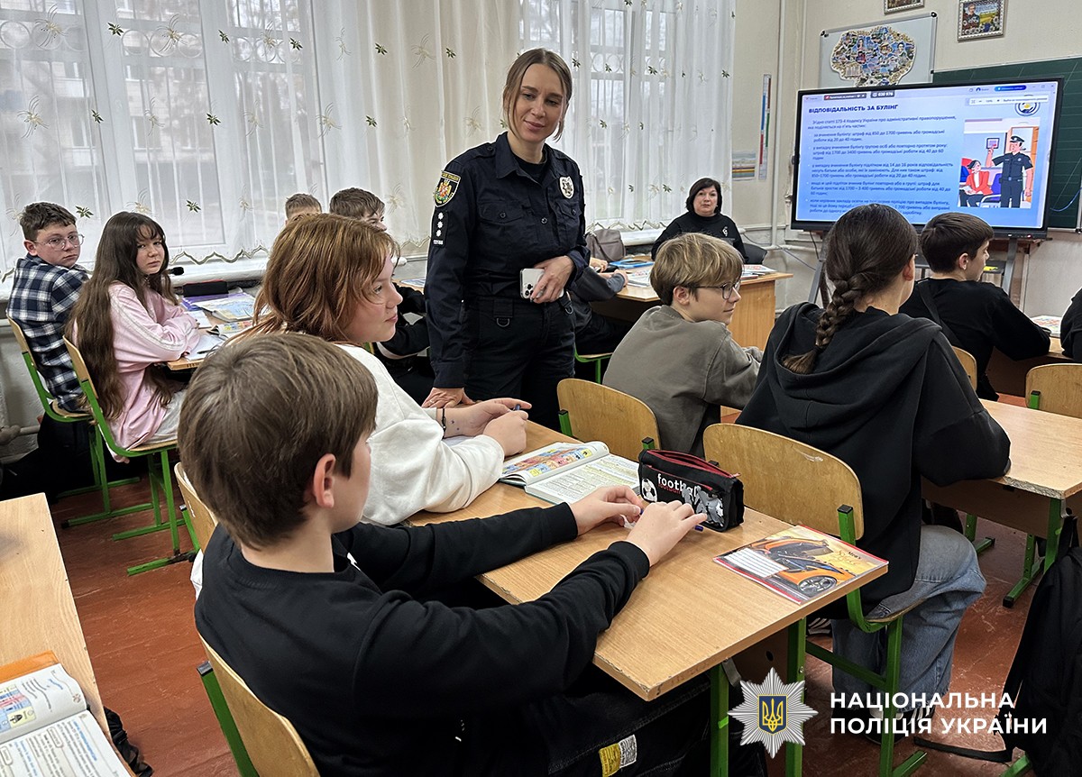 Учні сидять за партами, на задньому плані демонструється слайд із текстом про булінг. Поліцейська слухає одного із учнів.