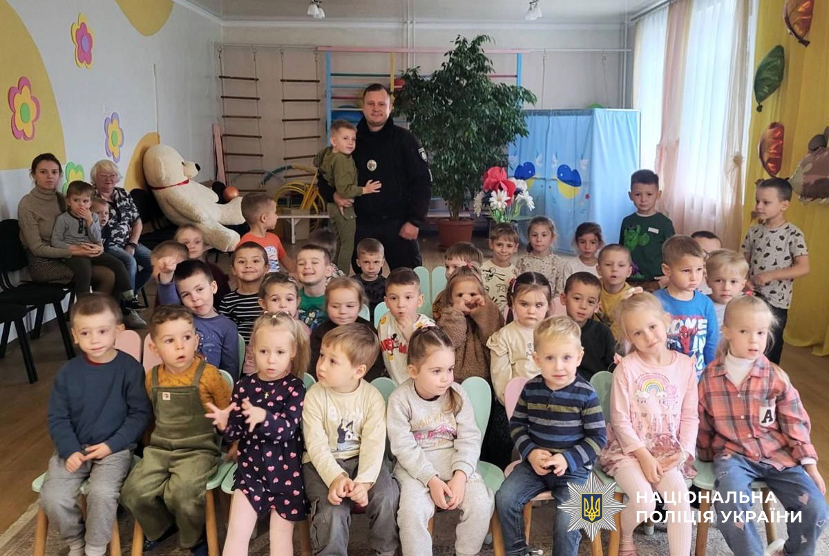 поліцейський із дітьми у дитсадку позують для спільного фото