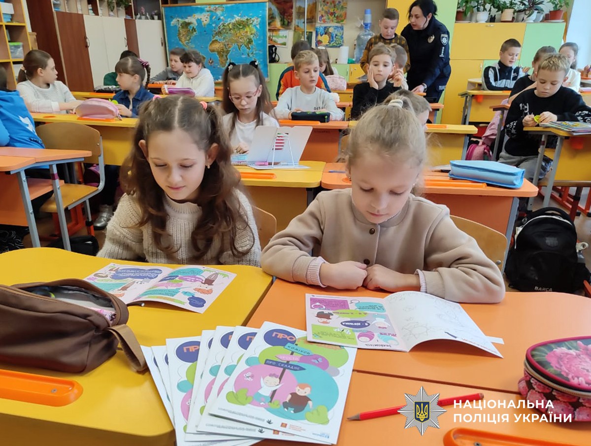 діти у класі за партами читають інформаційні брошури