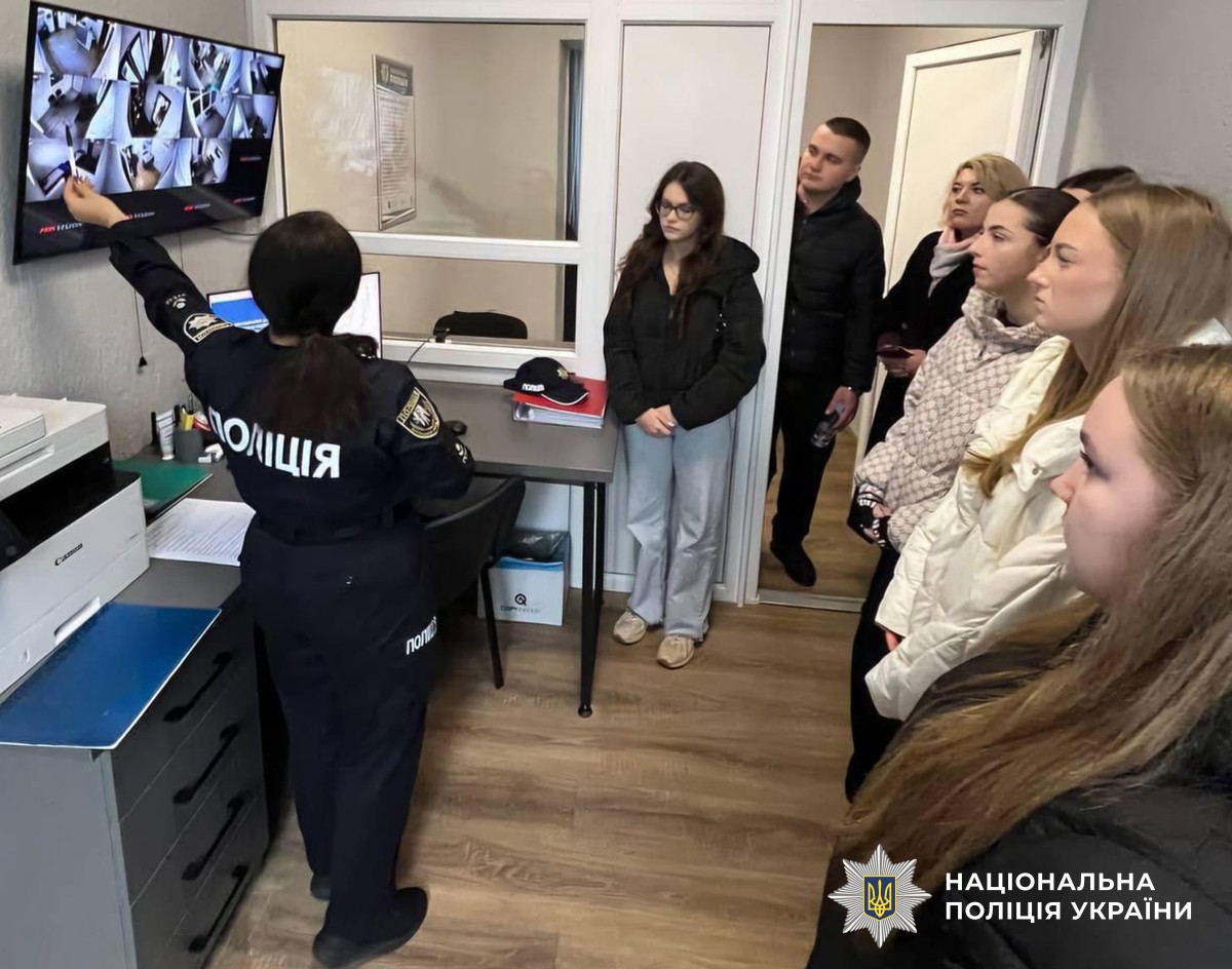 Поліцейська показує студентам зображення з камер відеонагляду на екрані