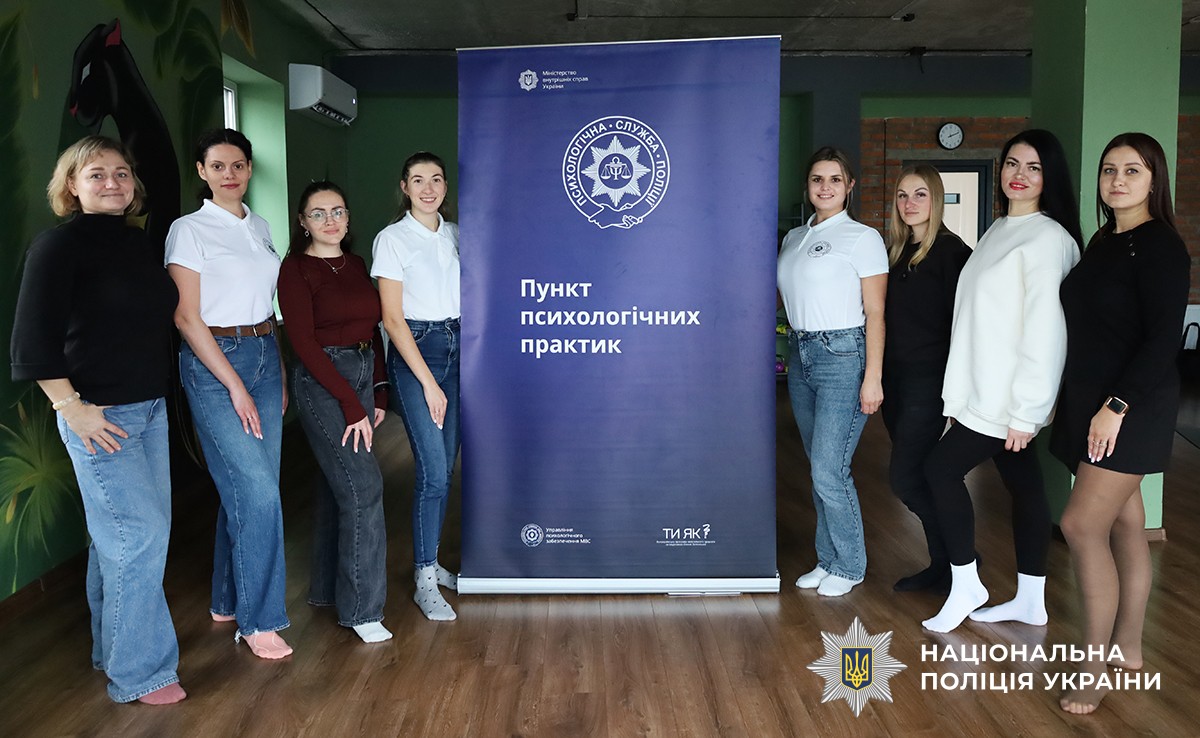учасники позують на спільному фото. Посередині між ними стоїть синій банер з емблемою та написом "пункт психологічних практик".