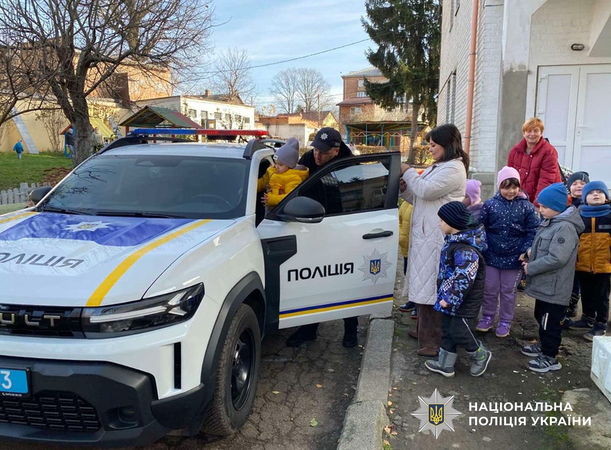 Поліцейський садить дитину до службового автомобіля