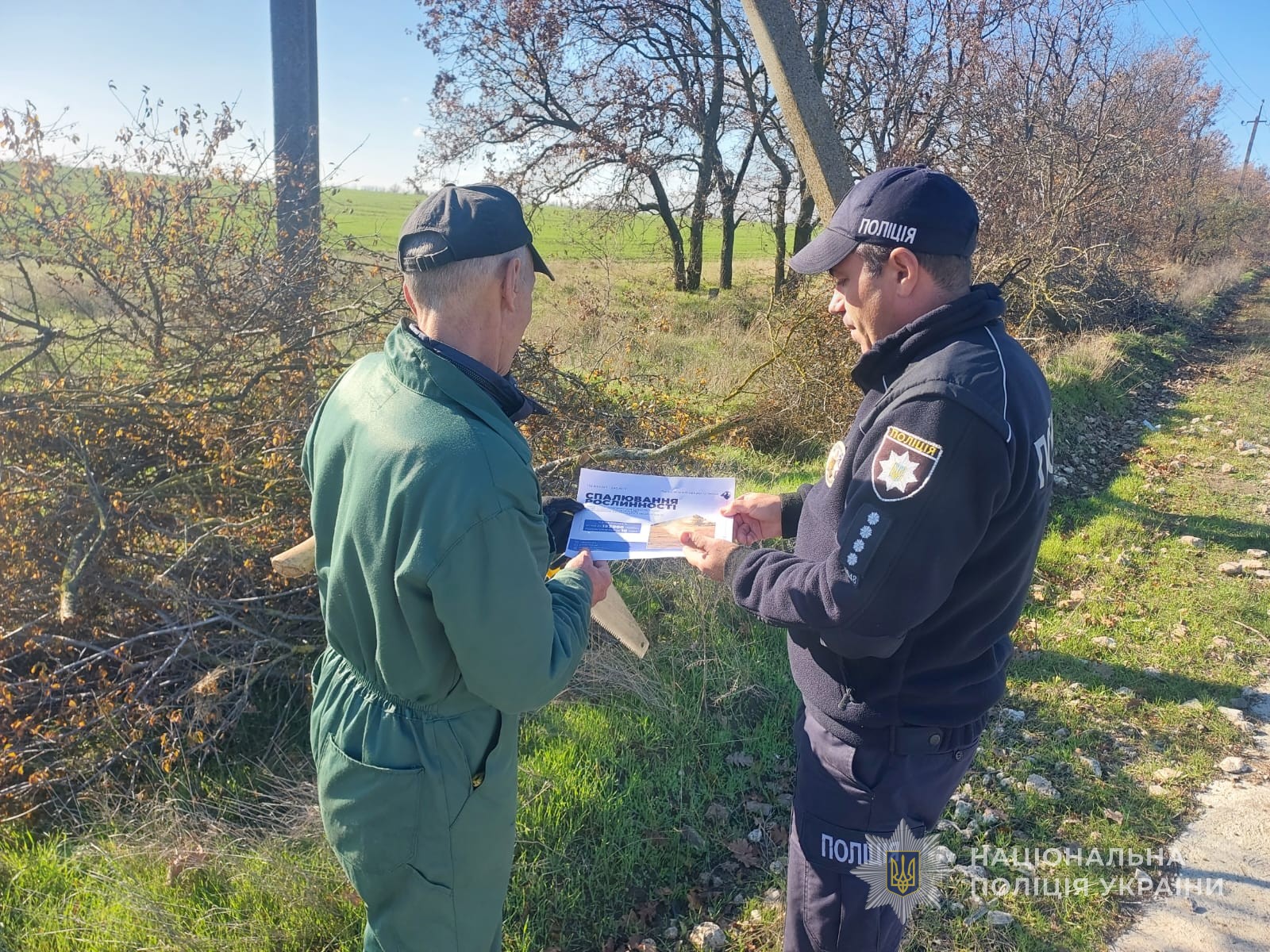 Поліцейський розповідає чоловікові про заборону спалювання листя та трави