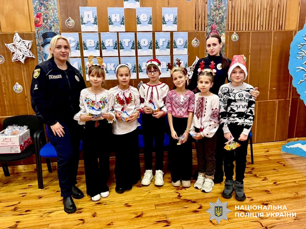 Дівчатка у вишиванках та зі святковими прикрасами стоять разом з двома офіцерками поліції
