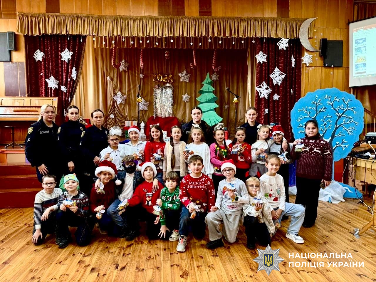 Діти у святкових костюмах та поліцейські позують разом перед сценою