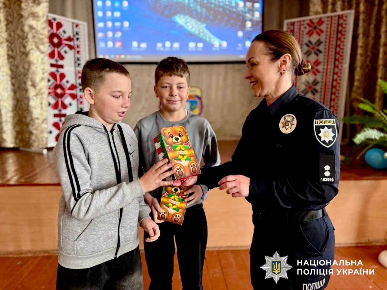Поліцейська передає подарунки двом хлопчикам