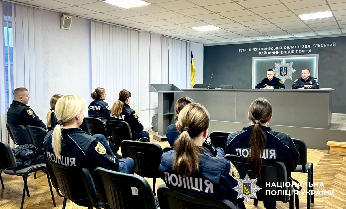 поліцейські та рятувальники на нараді. попереду - трибуна, за якою двоє виступаючих