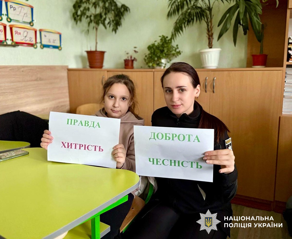 Поліціянтка та учениця тримають у руках аркуші з інформаційними написами