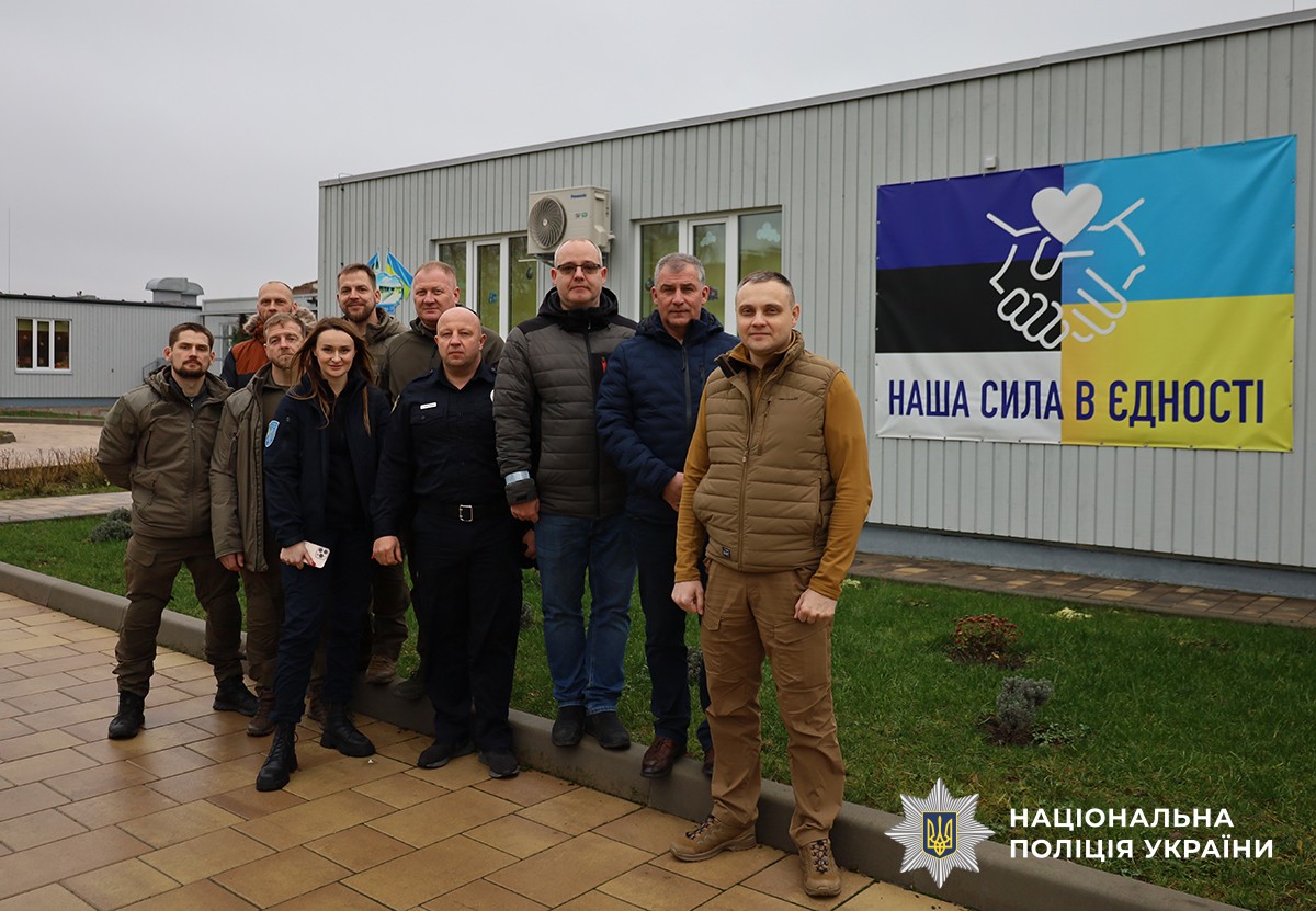 Спільне фото представників з Естонії та поліцейських. На стіні будівлі позаду видно великий банер із поєднаними кольорами прапорів Естонії та України, стилізованим зображенням рукостискання та написом «Наша сила в єдності».