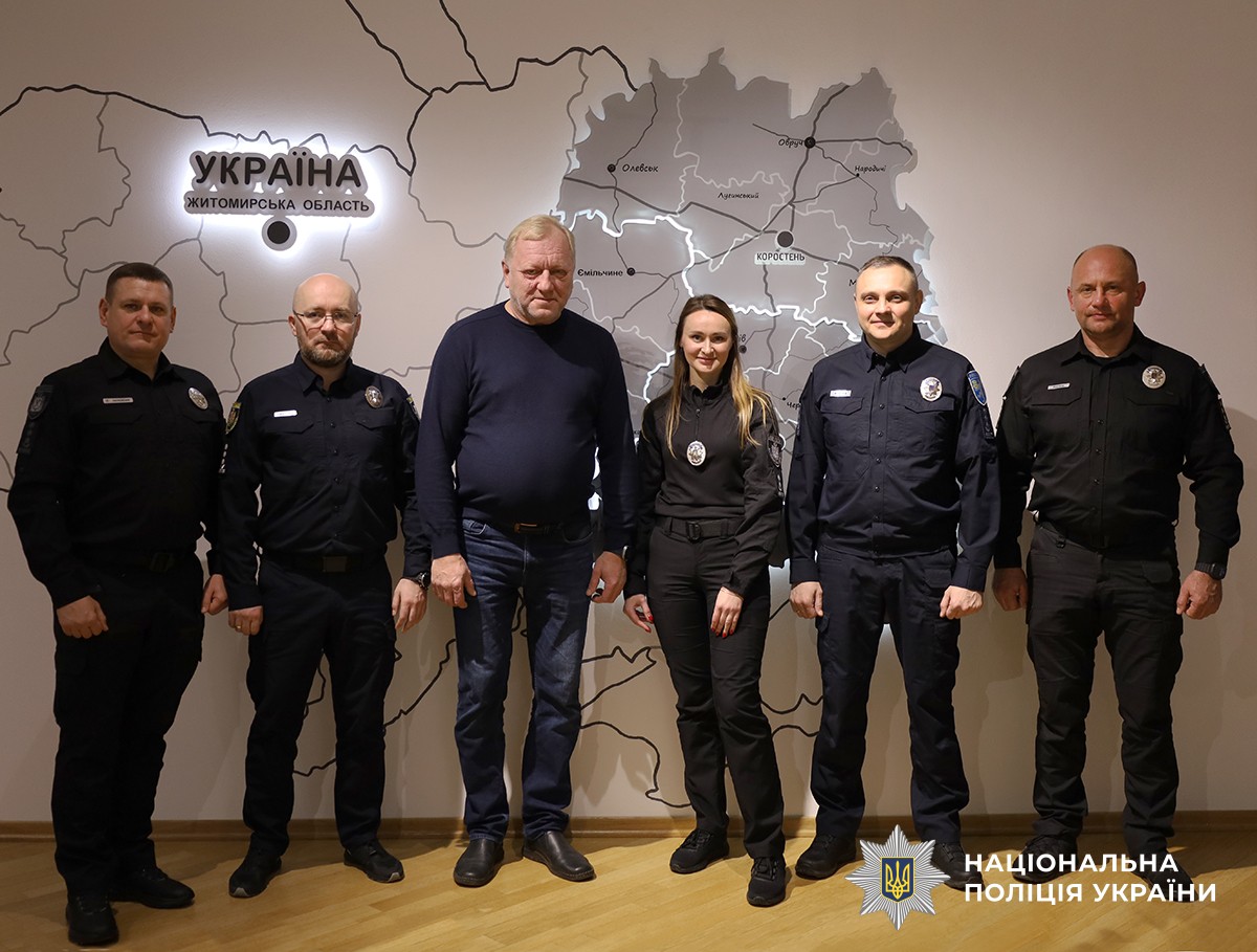 Спільне фото представника Естонії та поліцейських. На стіні позаду - велика карта України з виділеним контуром Житомирської області.