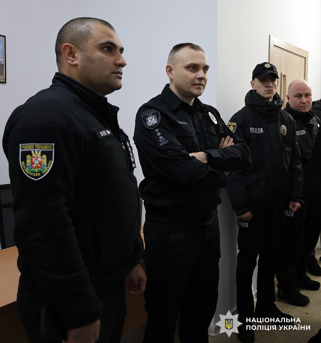 Поліцейські стоять вряд у приміщенні.