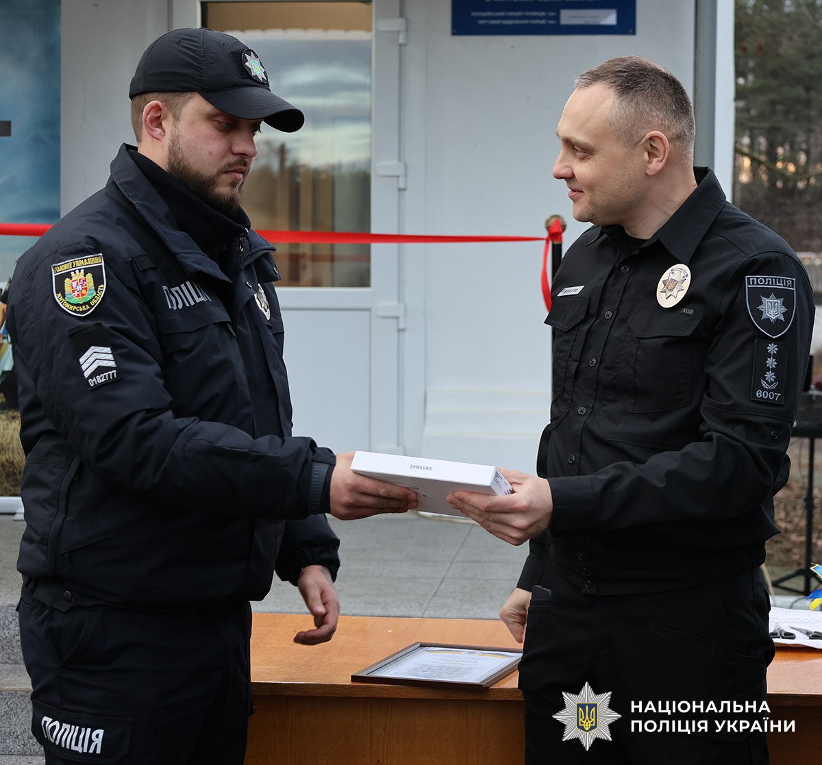Начальник поліція вручає планшетний пристрій поліцейському, на вулиці.