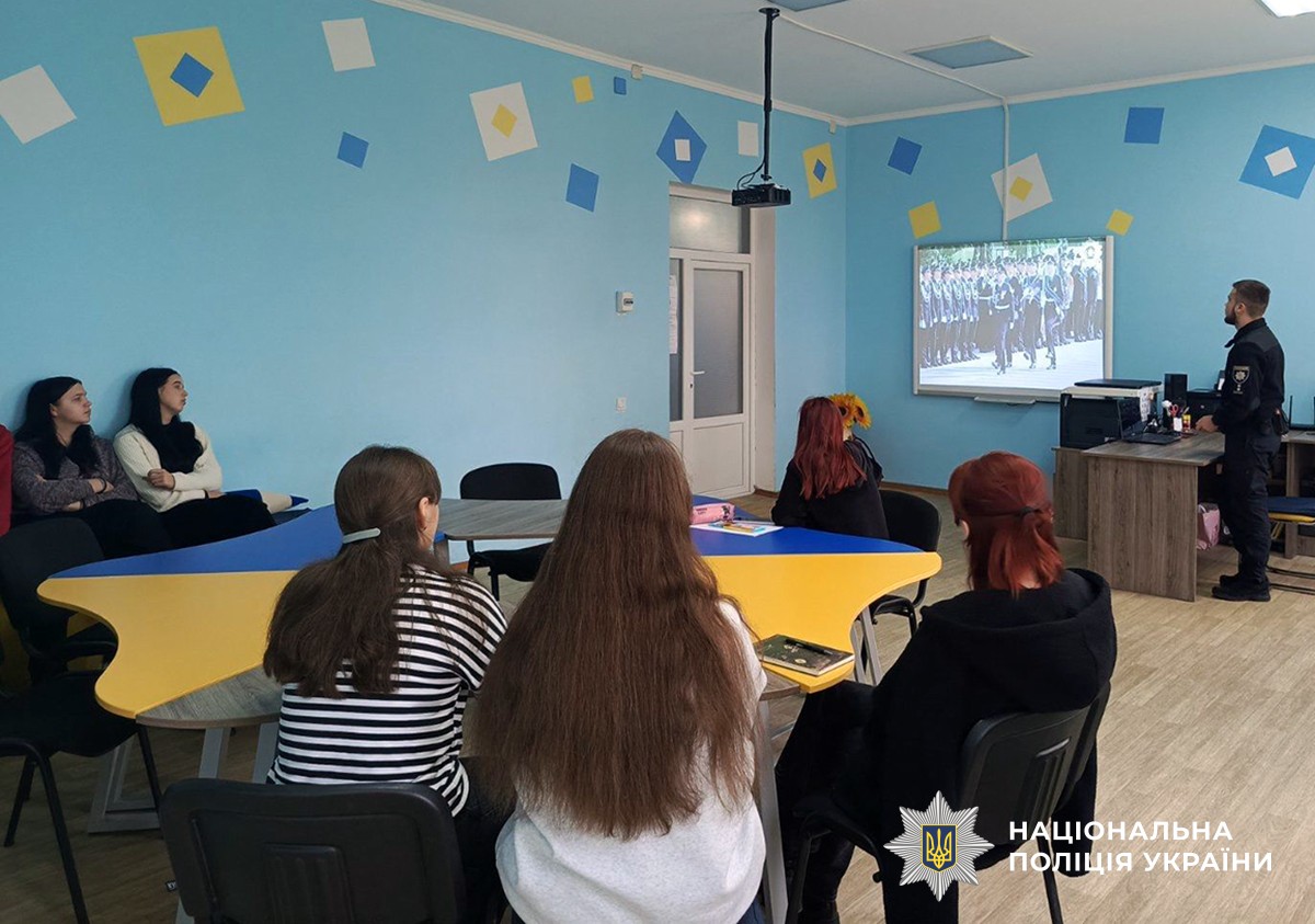 поліцейський у навчальному класі показує учням ролик про курсантів