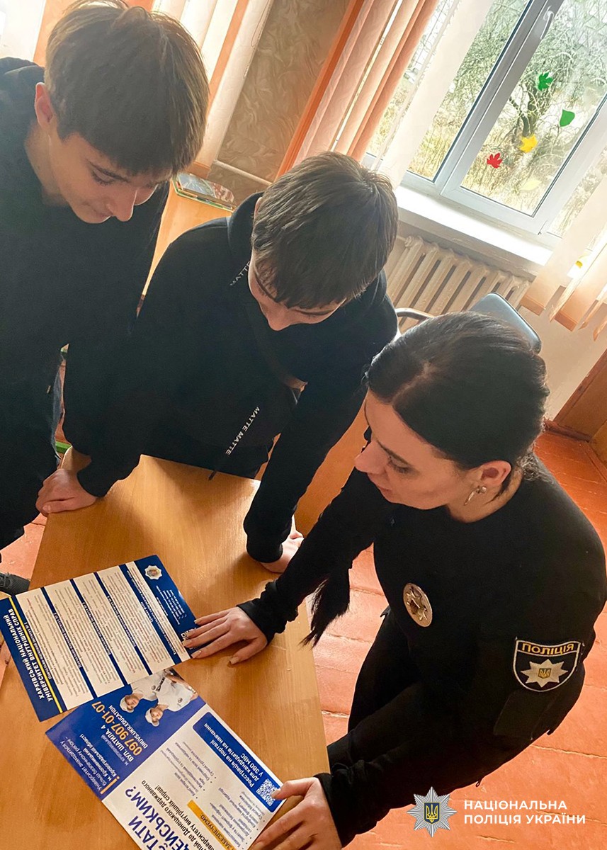 поліцейські з учнями розглядає рекламну продукцію щодо вступу до закладів МВС