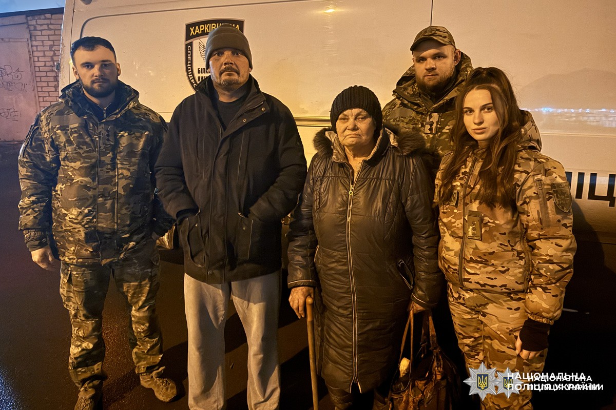 Поліцейські та цивільні біля білого мікроавтобуса.