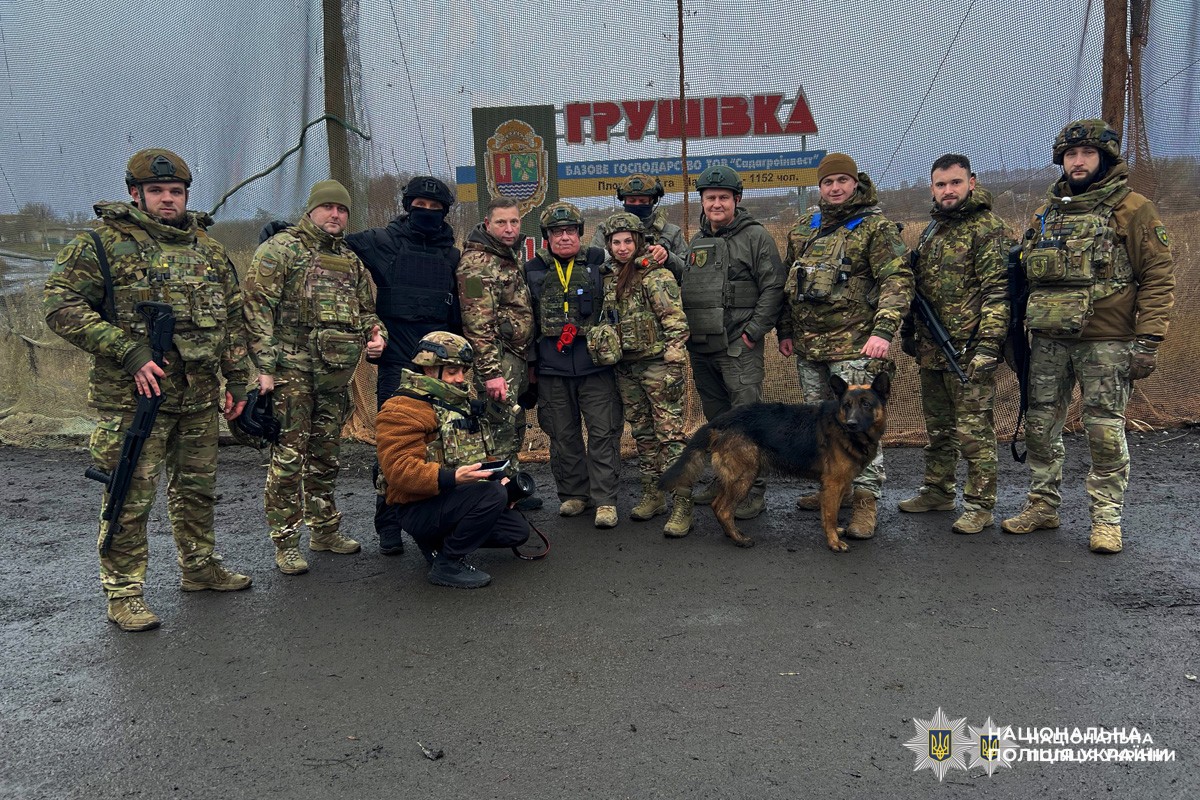 Поліцейські та військові у спорядженні стоять разом.