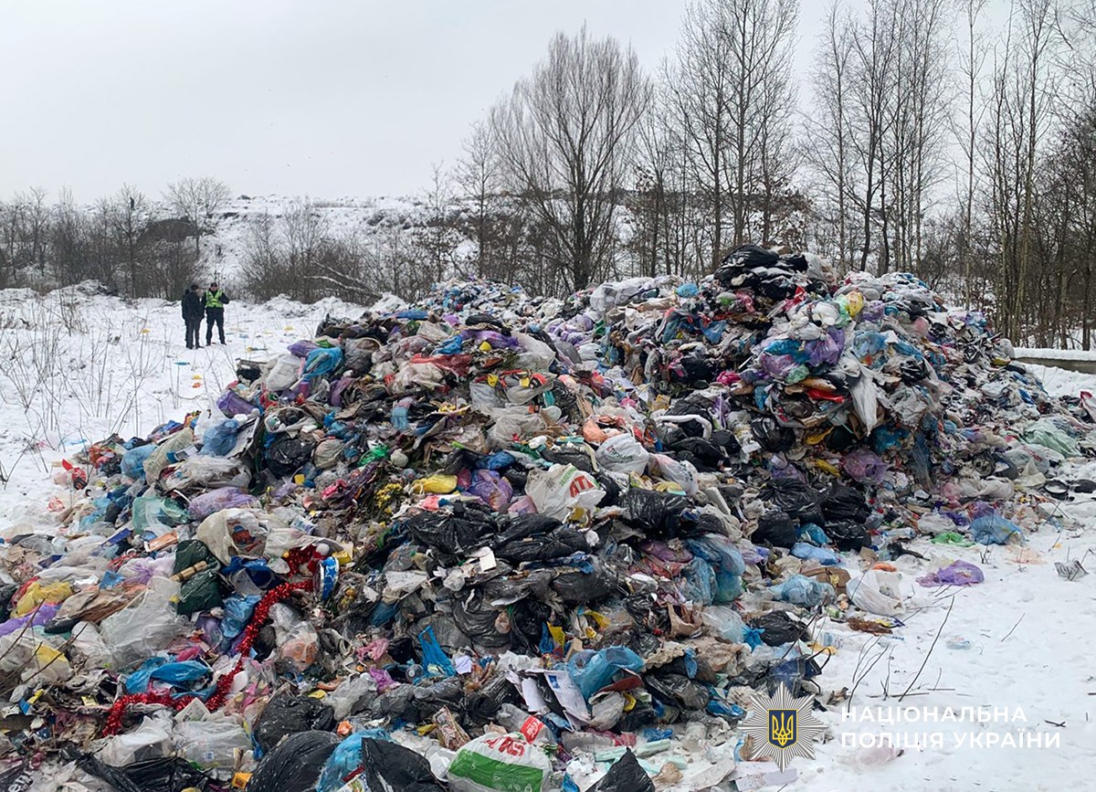 купа сміття на відкритій ділянці місцевості. поблизу стоїть поліцейський і ще одна людина