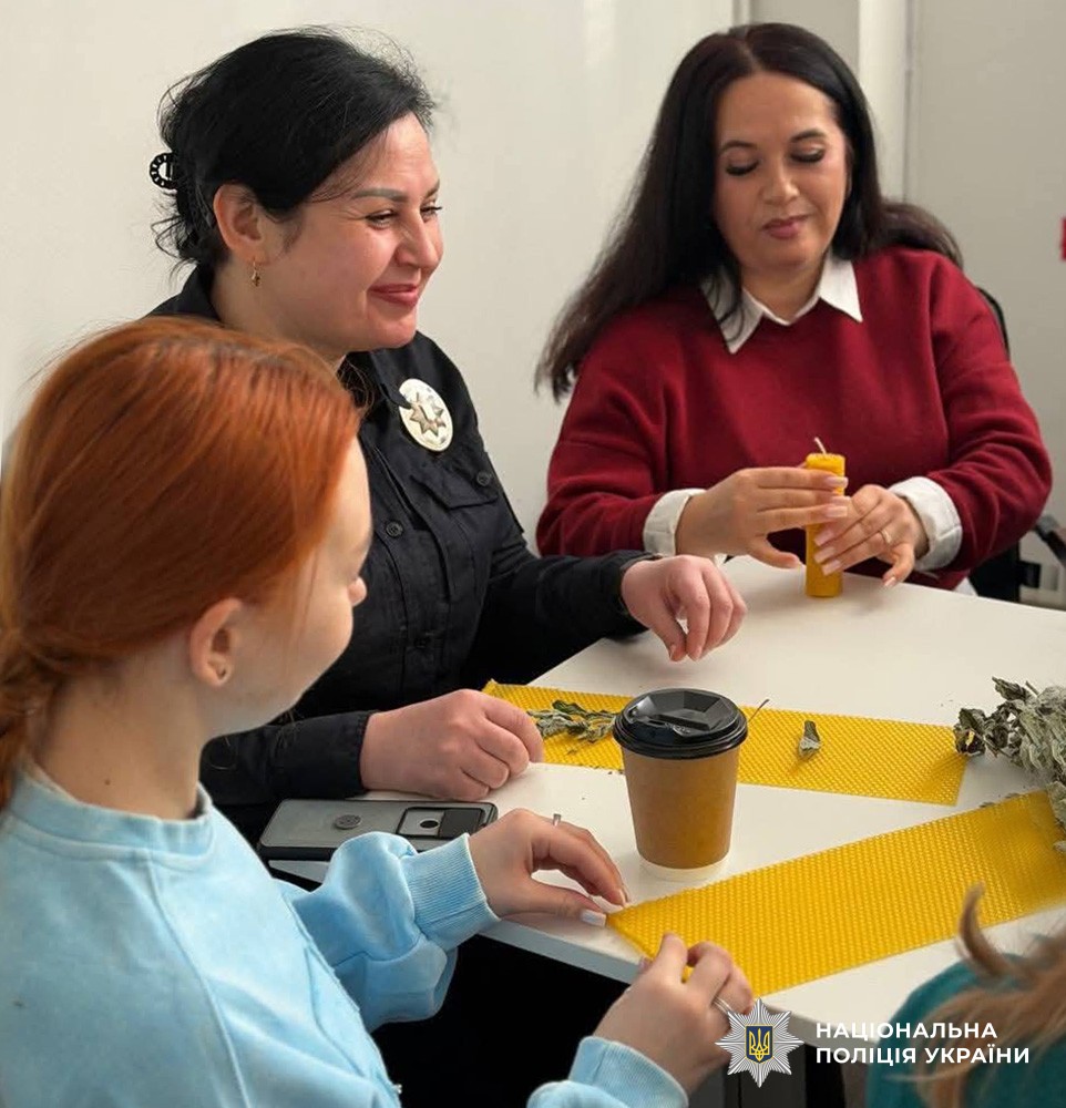 поліцейська та учасники заходу виготовляють свічки за столом