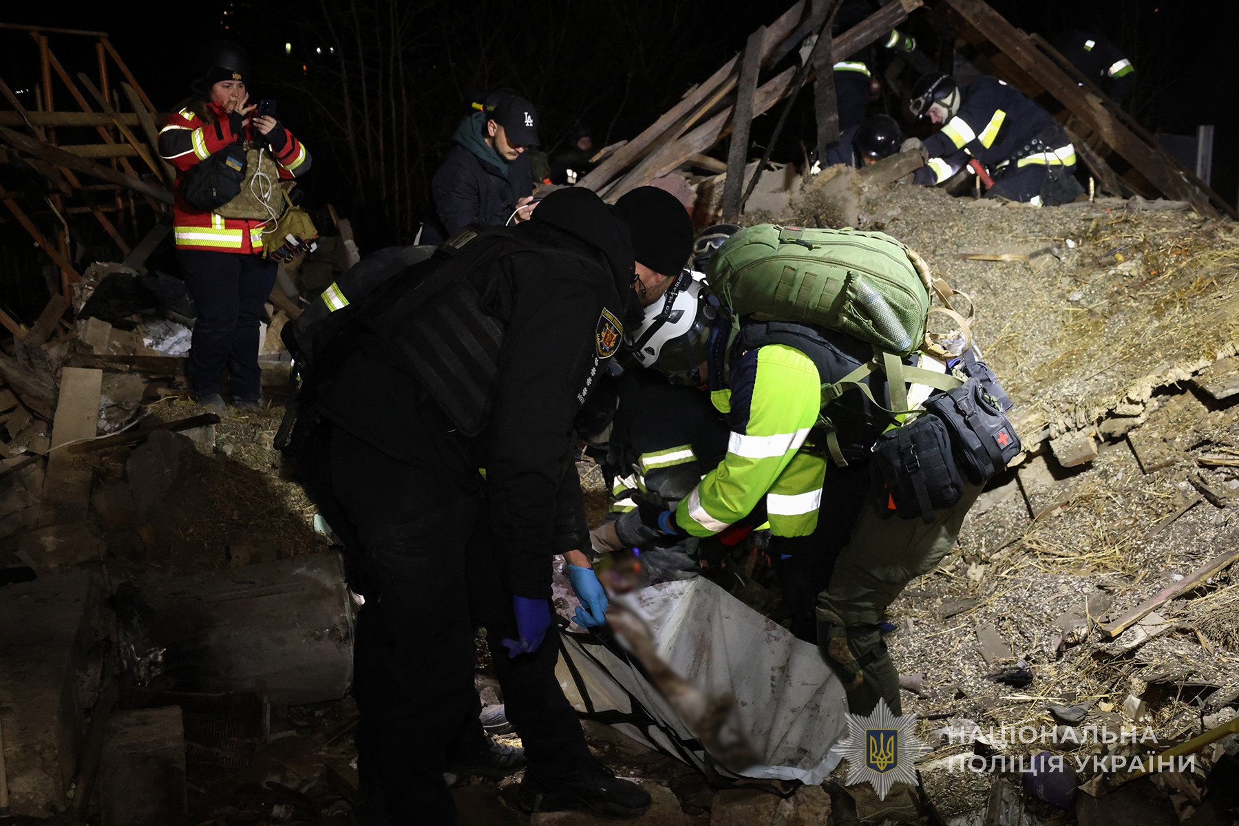 Поліцейський допомагає дістати з-під руїн тіло людини, загиблої внаслідок ракетного удару росіян по обласному центру. Березень 2025 року.