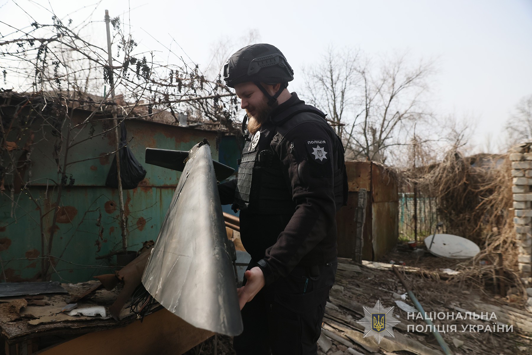 Поліцейський офіцер громади тримає в руках частину ворожого ударного безпілотника. Місто Гуляйполе. Березень 2025 року.