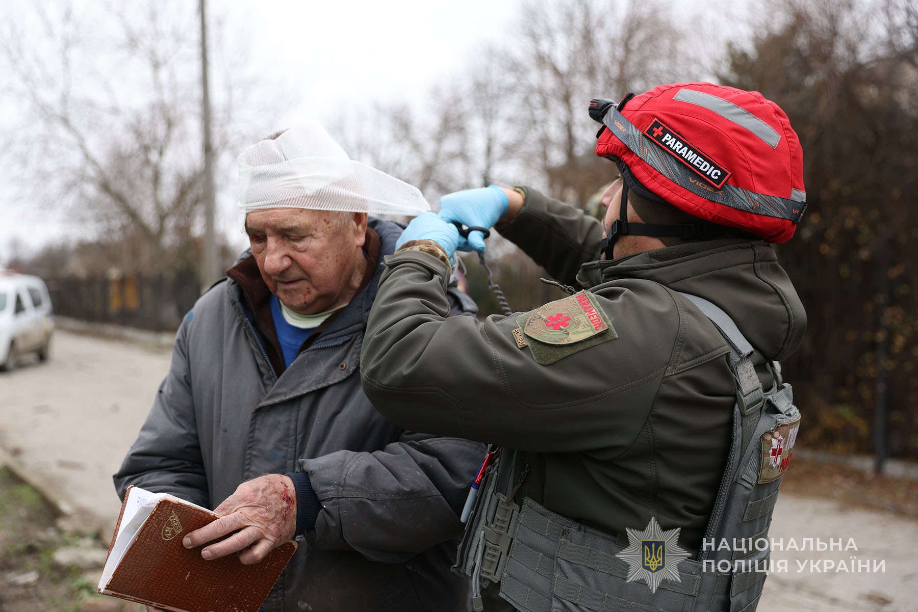 Парамедик запорізької поліції надає допомогу чоловіку, пораненому внаслідок ворожого авіаудару. Селище Кушугум. Грудень 2025 року.