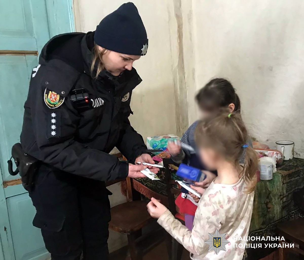 Поліцейська дає засоби гігієни двом дівчаткам