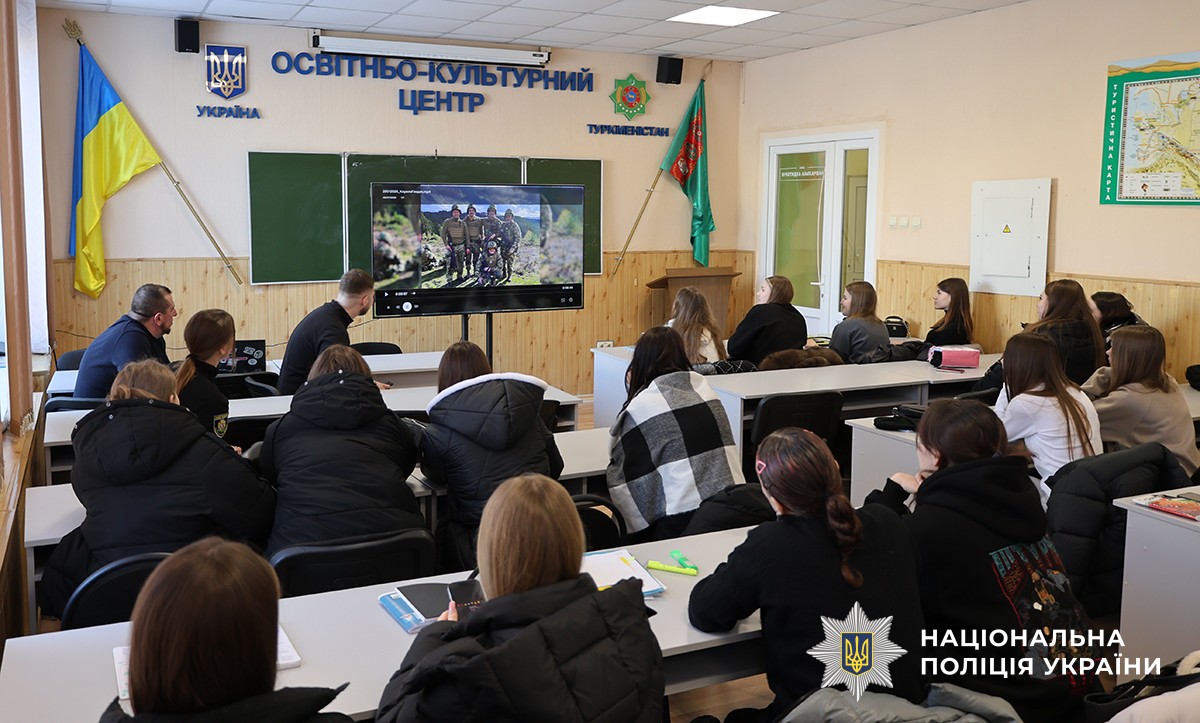 Студенти сидять за партами в аудиторії та разом із ветеранами переглядають на екрані відеоролик, присвячений службі у збройних силах.