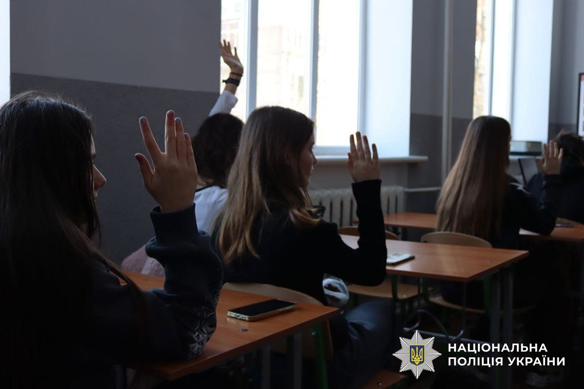 Учні сидять за партами та піднімають руку догори.