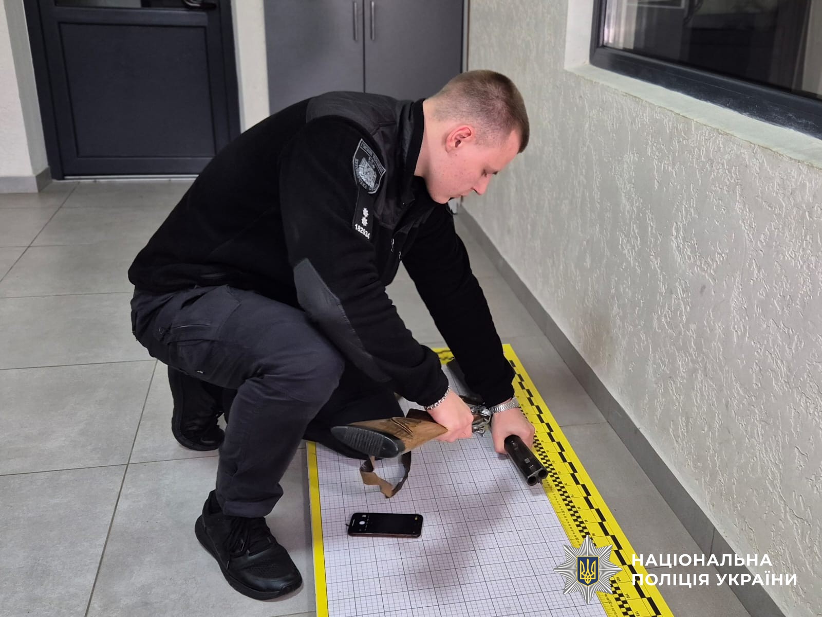 Поліцейський розташовує рушницю для її вимірювання на спеціальній поверхні