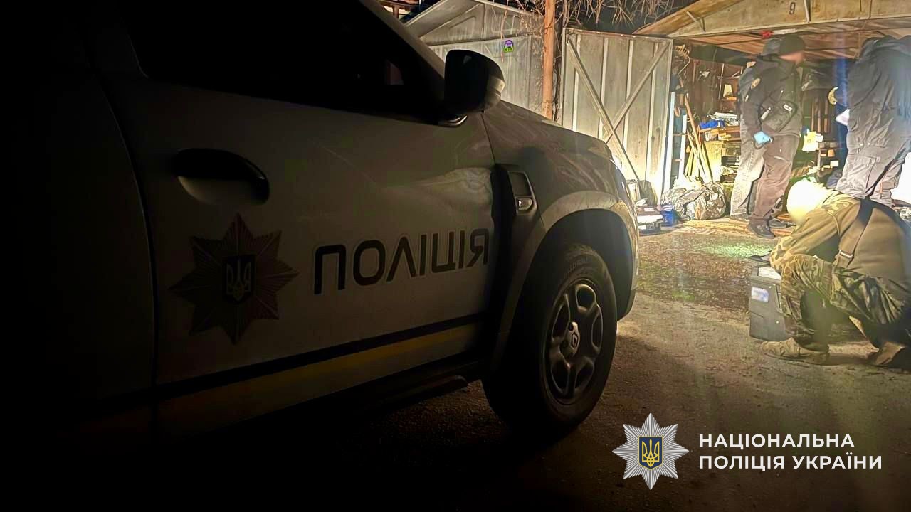 Поліцейське авто та правоохоронці на місці проведення обшуків у гаражному приміщенні