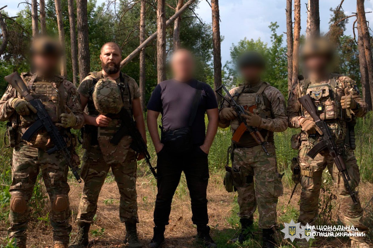 Група з чотирьох у камуфляжі та одного цивільного, обличчя частково розмиті.