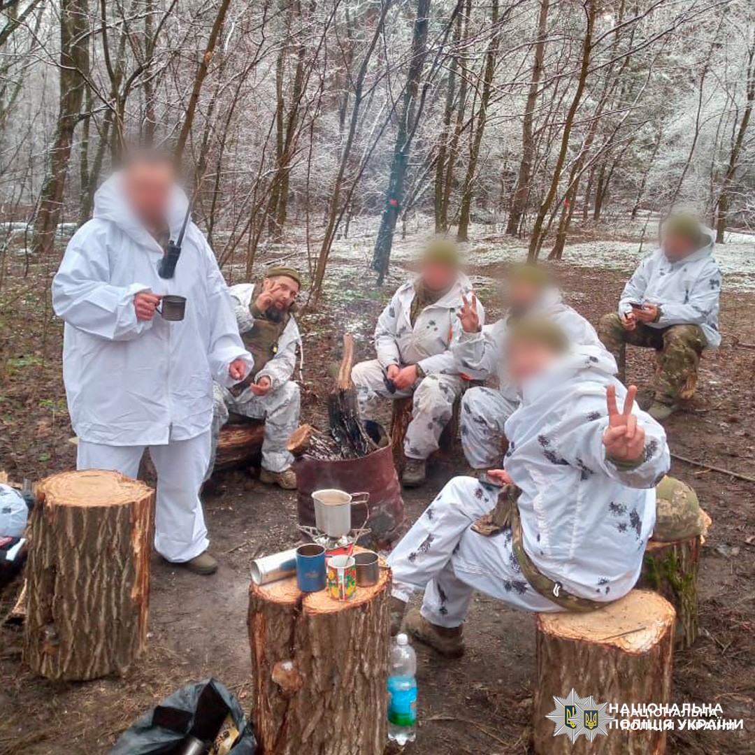 Поліцейські у зимовому камуфляжі гріються біля багаття та діляться теплом у польових умовах.