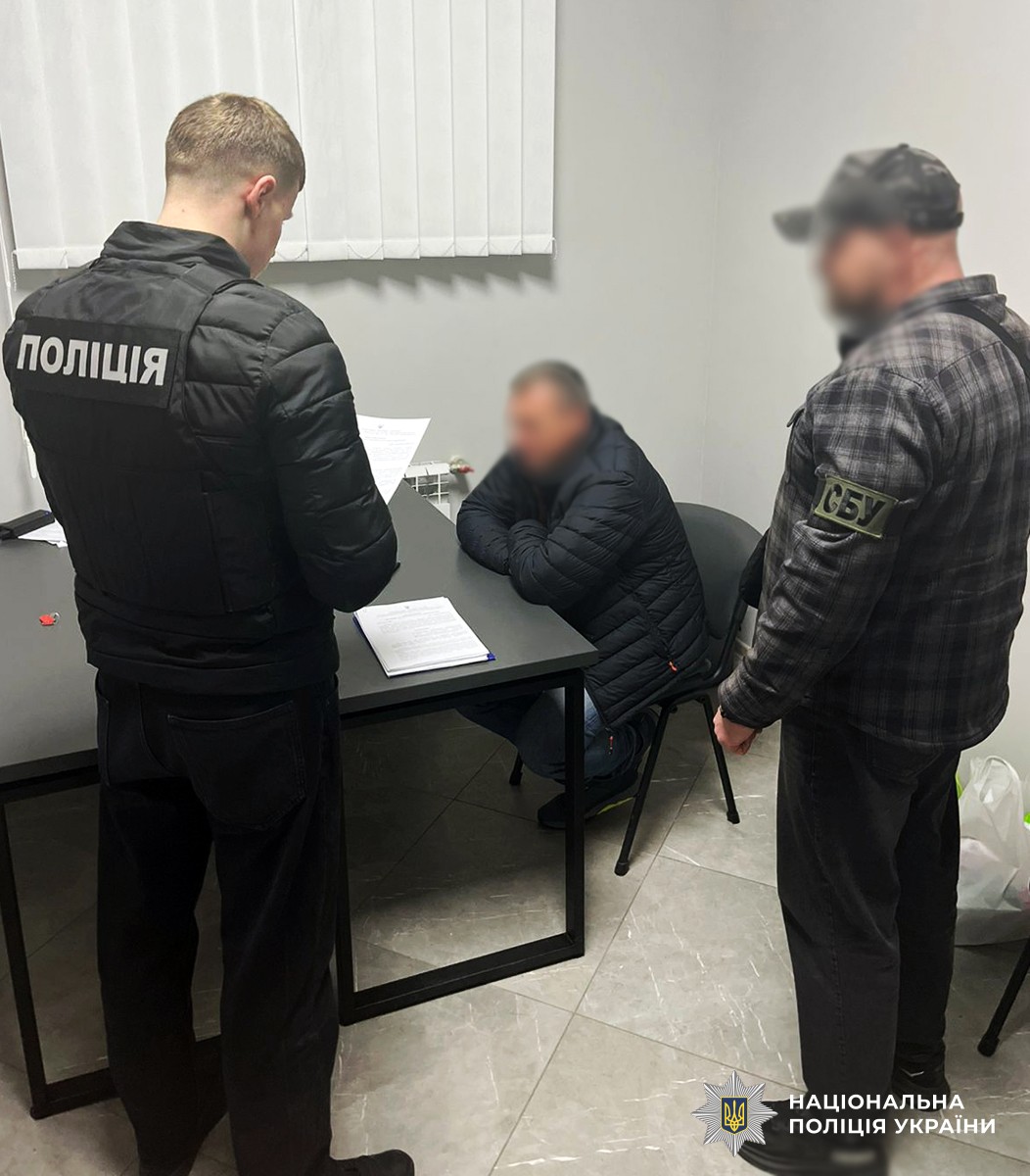 поліцейський та співробітник УСБУ вручають підозрюваному документи