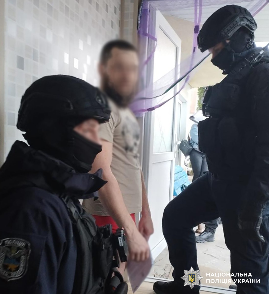 Спецпризначенці поліції стоять з обох боків від затриманого чоловіка