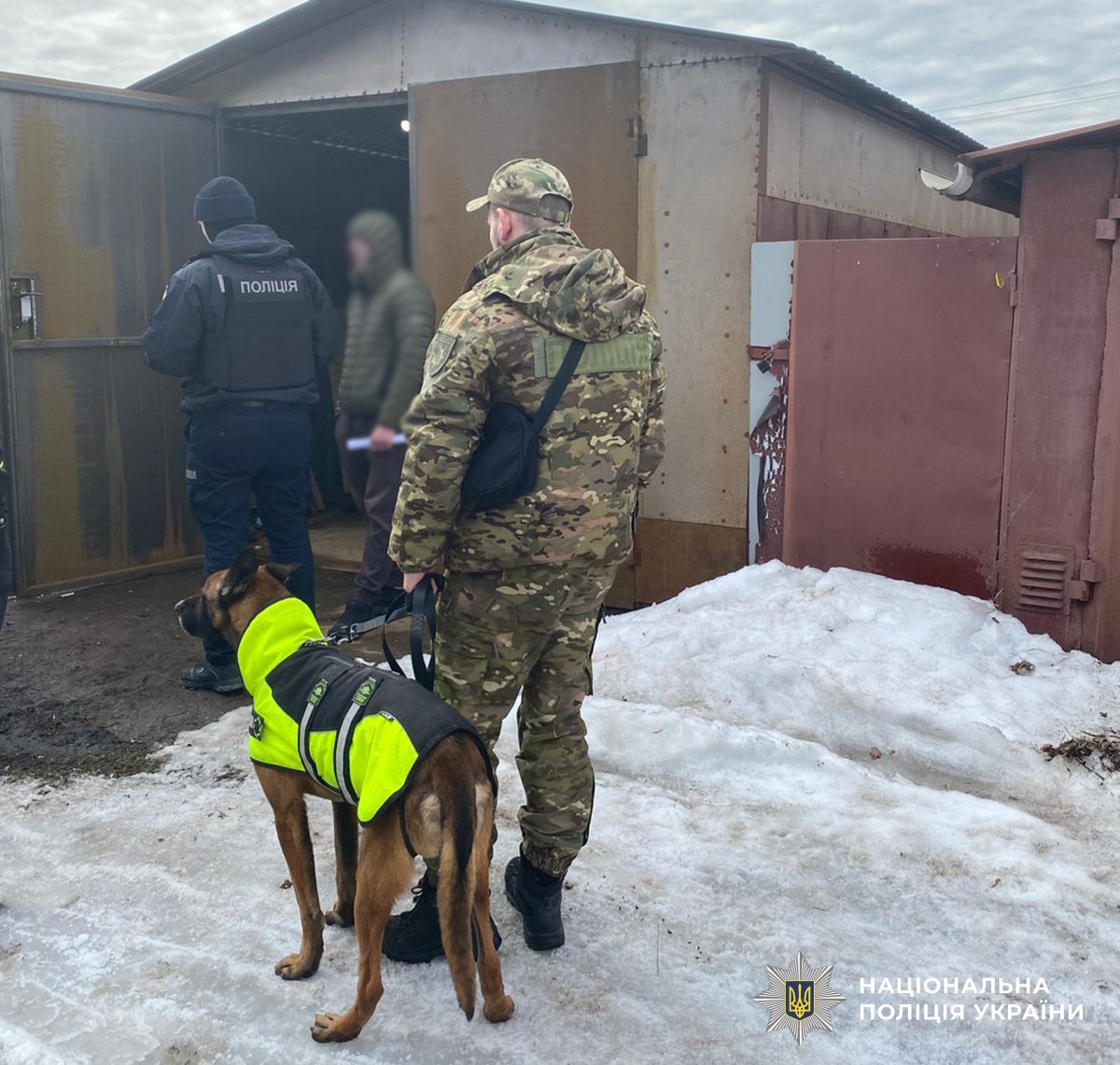 Слідчий поліції та кінолог з собакою стоять біля гаража