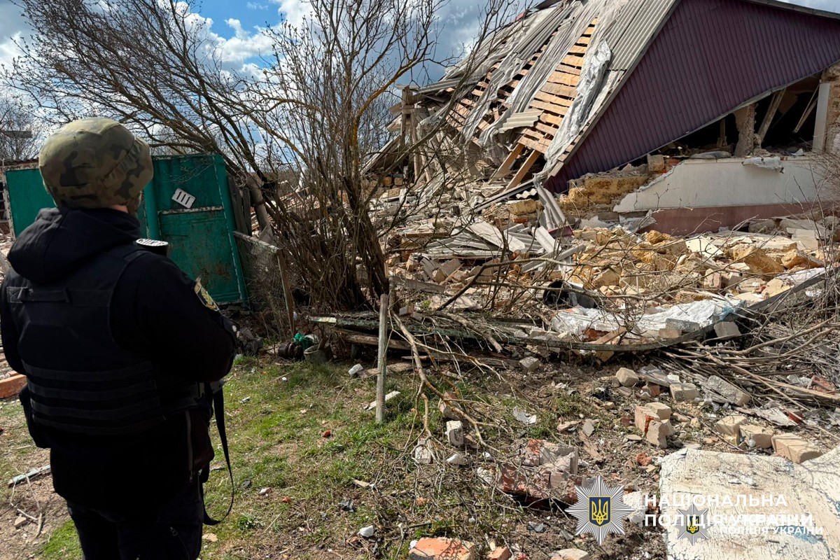 Поліцейський у захисному спорядженні оглядає зруйновану будівлю. Зафіксовано значні пошкодження стін та даху.