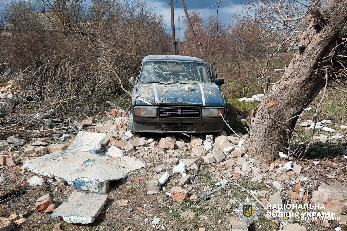 Синій автомобіль із розбитим склом, навколо уламки та зруйновані конструкції.