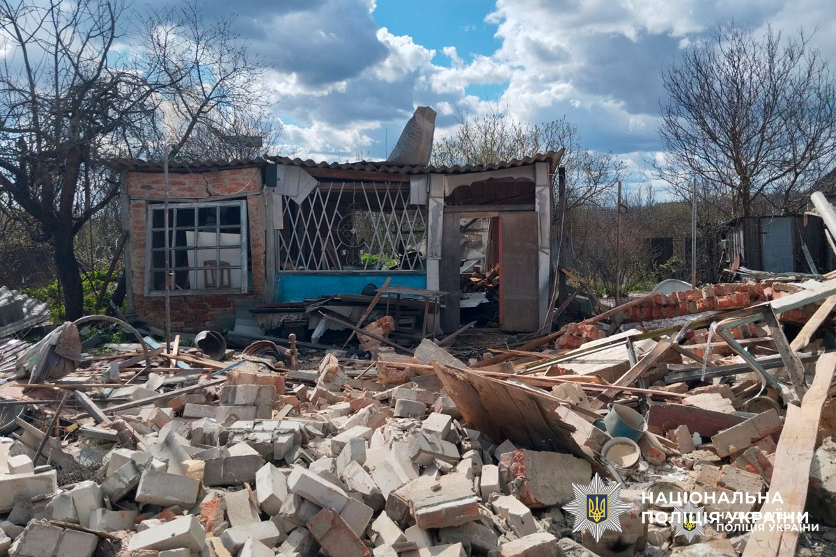 Цегляна будівля з обваленим дахом і розбитими вікнами, навколо уламки та побутові речі.