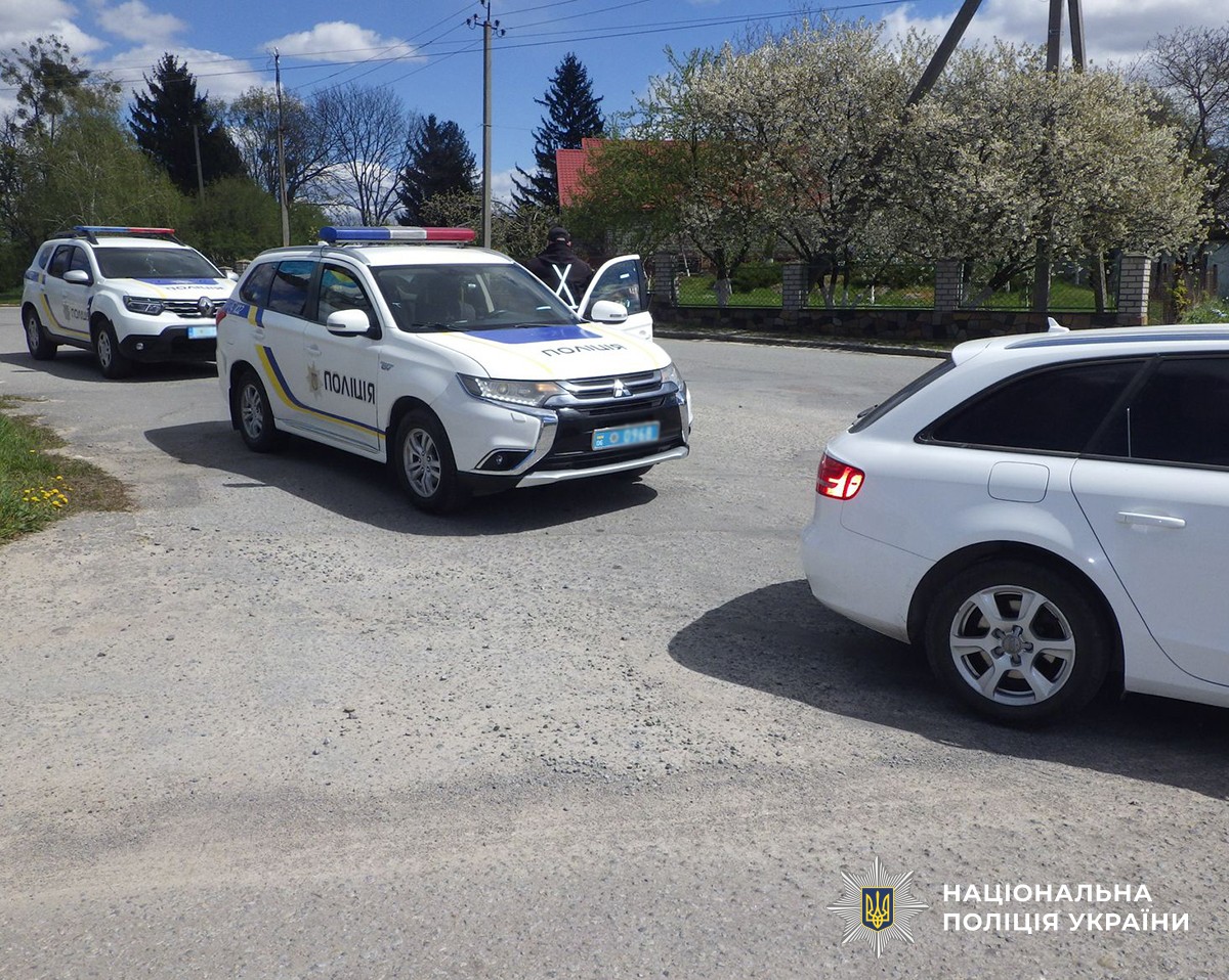 Автомобілі на дорозі, частково видно біле авто порушника та два службових автомобіля поліції