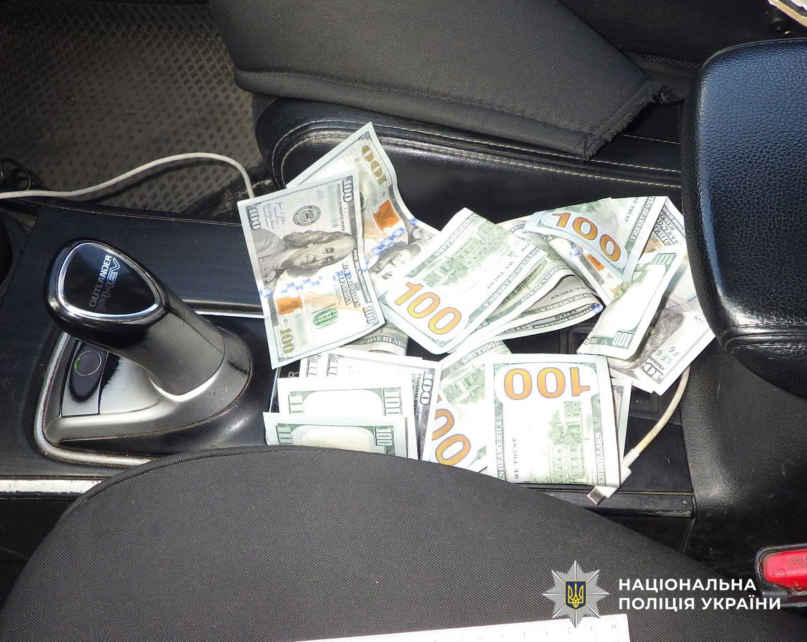 Гроші в доларах США лежать між передніми сидіннями в салоні авто