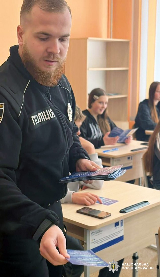 Поліцейський роздає ліцеїстам інформаційні листівки