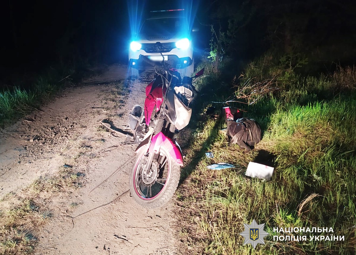 Мотоцикл на грунтовій дорозі, позаду стоїть автомобіль поліції