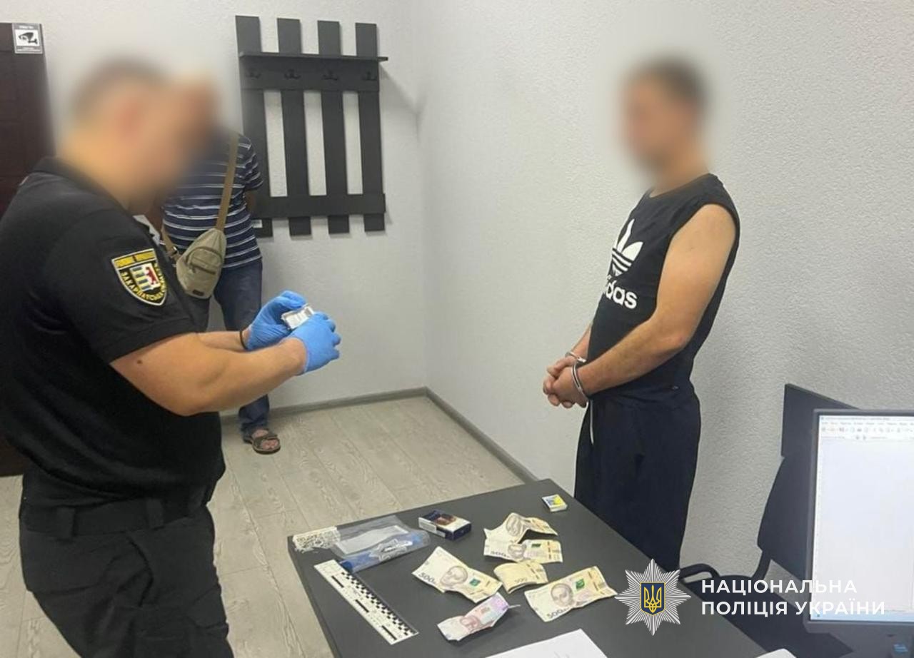 Поліцейський вилучає речові докази у фігуранта — викрадену у потерпілих готівку